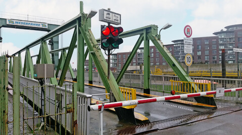 Old ferry pier at the Geeste estuary in Bremerhavem with a closed barrier and traffic lights